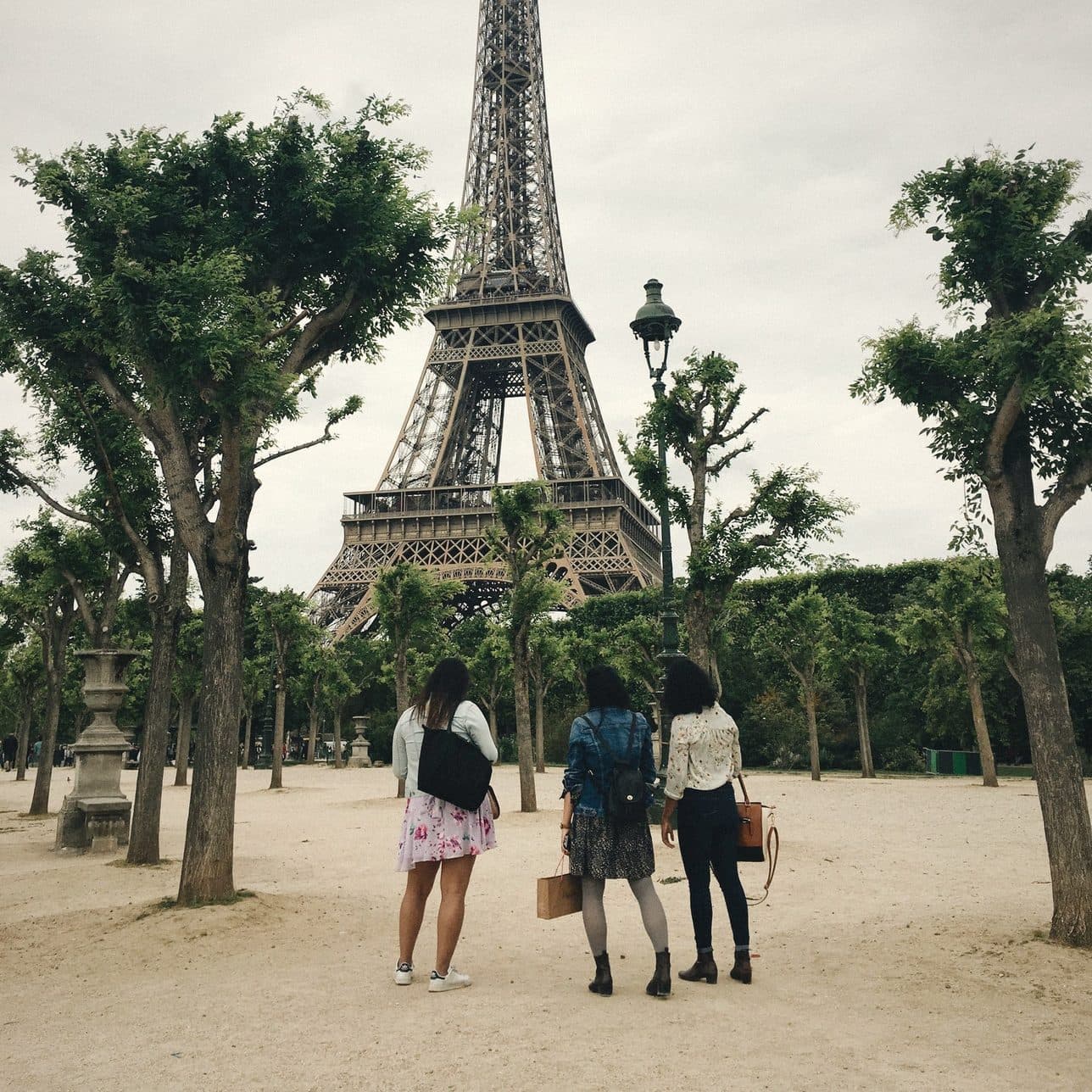 Three friends looking up at the Eiffel Tower through the trees