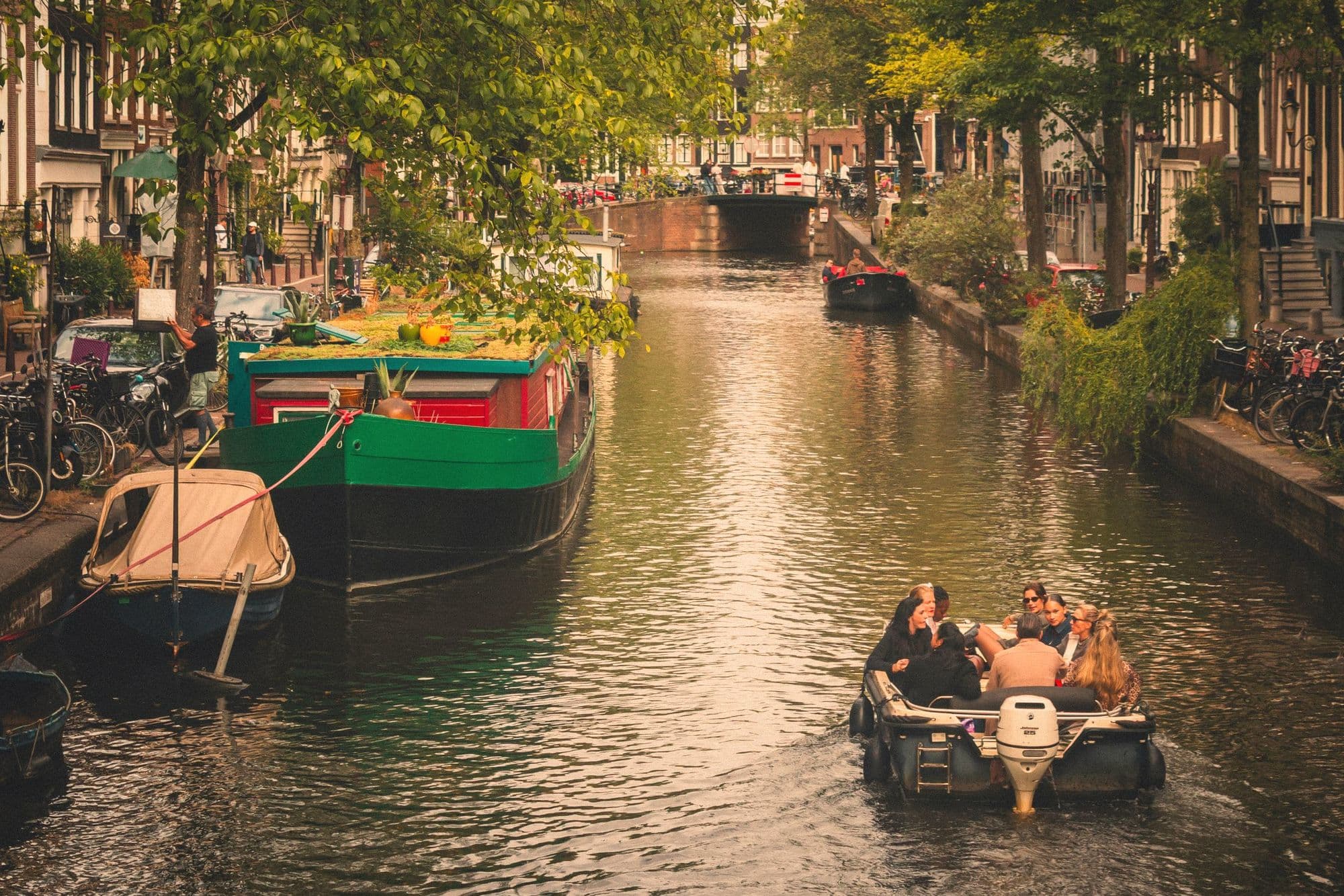 Friends in a small boat on an Amsterdam canal in evening light